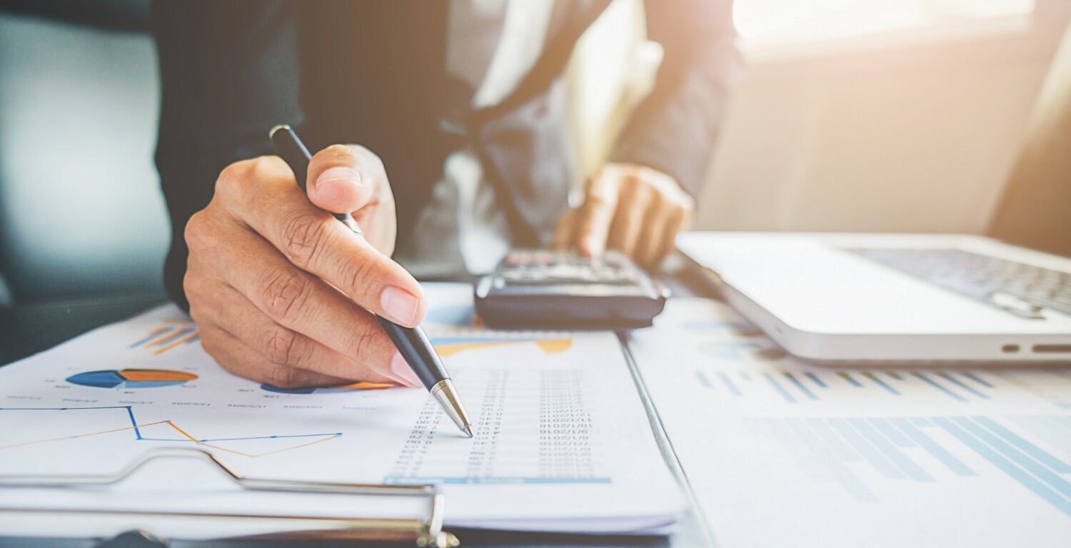 man using a calculator and writing on a clipboard