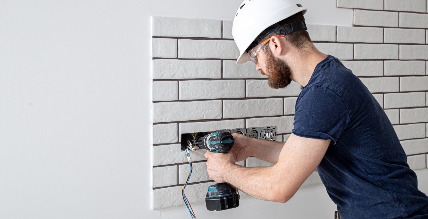 construction worker with a drill installing sockets