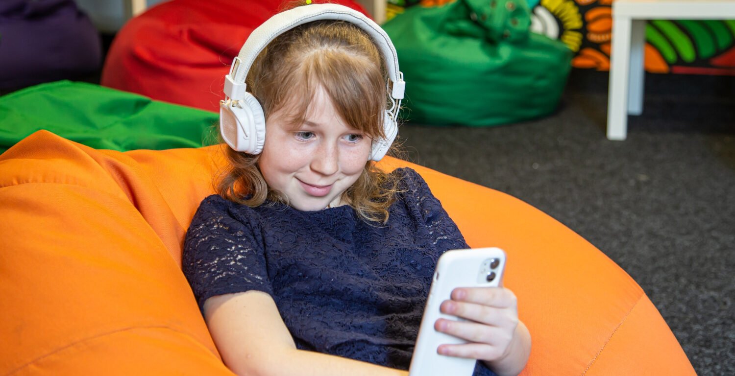 little girl using her phone and wearing headphones