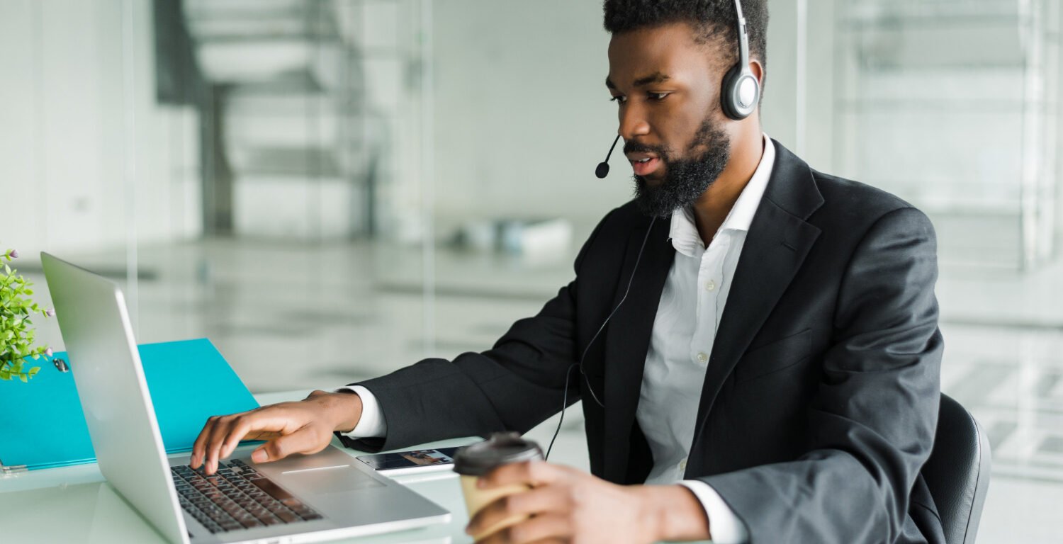 man using hands-free headset and laptop for work