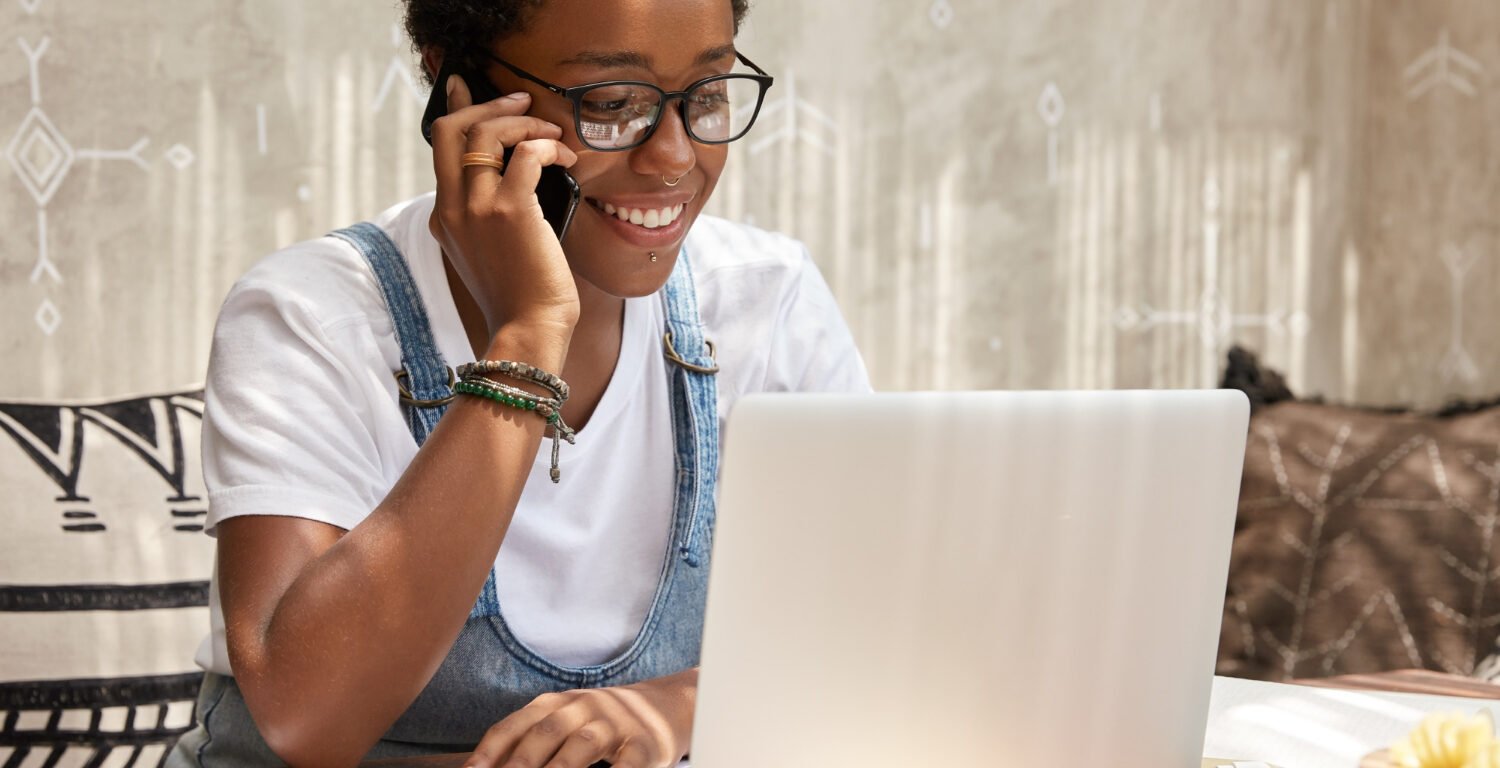 Woman working on a laptop while taking a call.