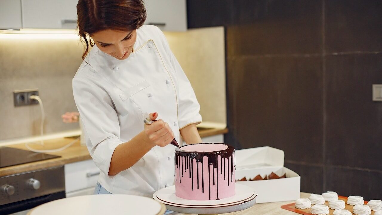 Female baker decorating a cake.