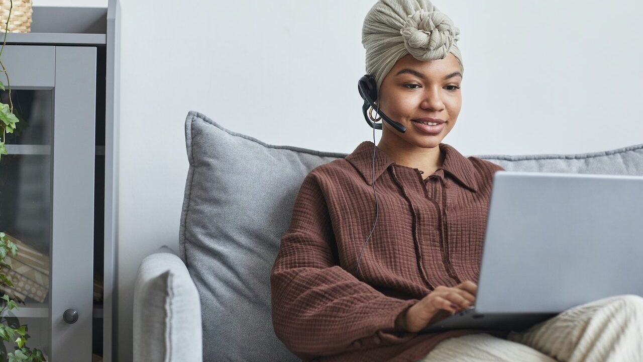 Woman wearing a headset and working on a laptop.